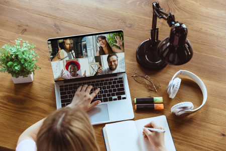 vrouw die thuis aan een bureau zit en in de camera kijkt