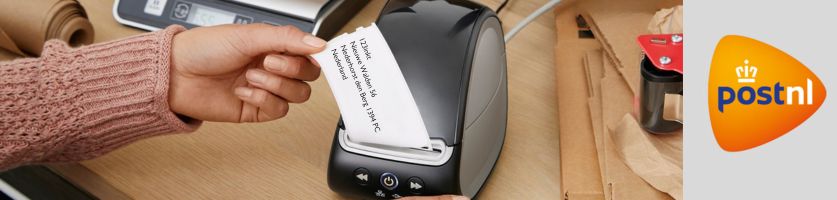 Hand scheurt een verzendetiket met adresgegevens uit een labelprinter