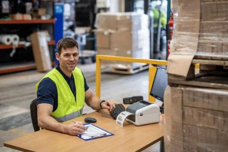 man in een magazijn die met een labelprinter werkt