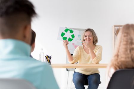 vrouw in een kantooromgeving die enthousiast een recycle-logo omhoog houdt