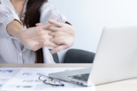 vrouw achter een laptop die haar armen strekt