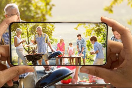 iemand die met een mobiele telefoon een foto van een zomers tafereel maakt